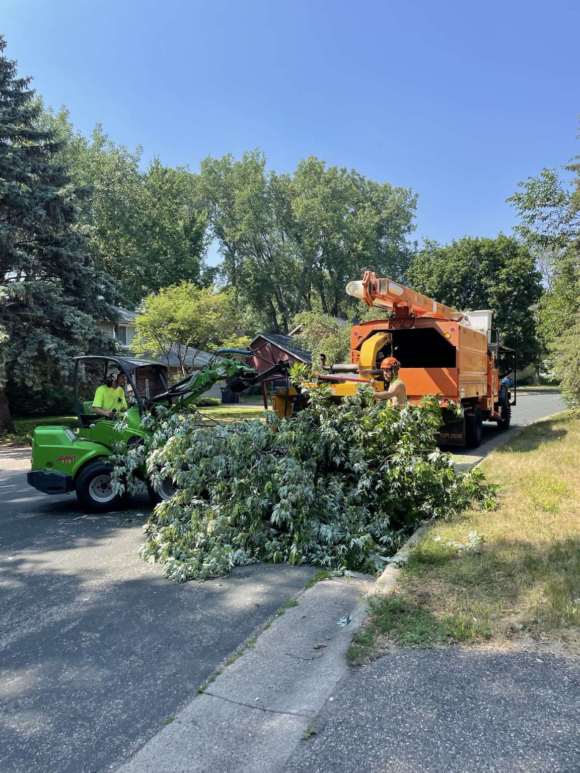 Crew cleaning up branches with chipper truck